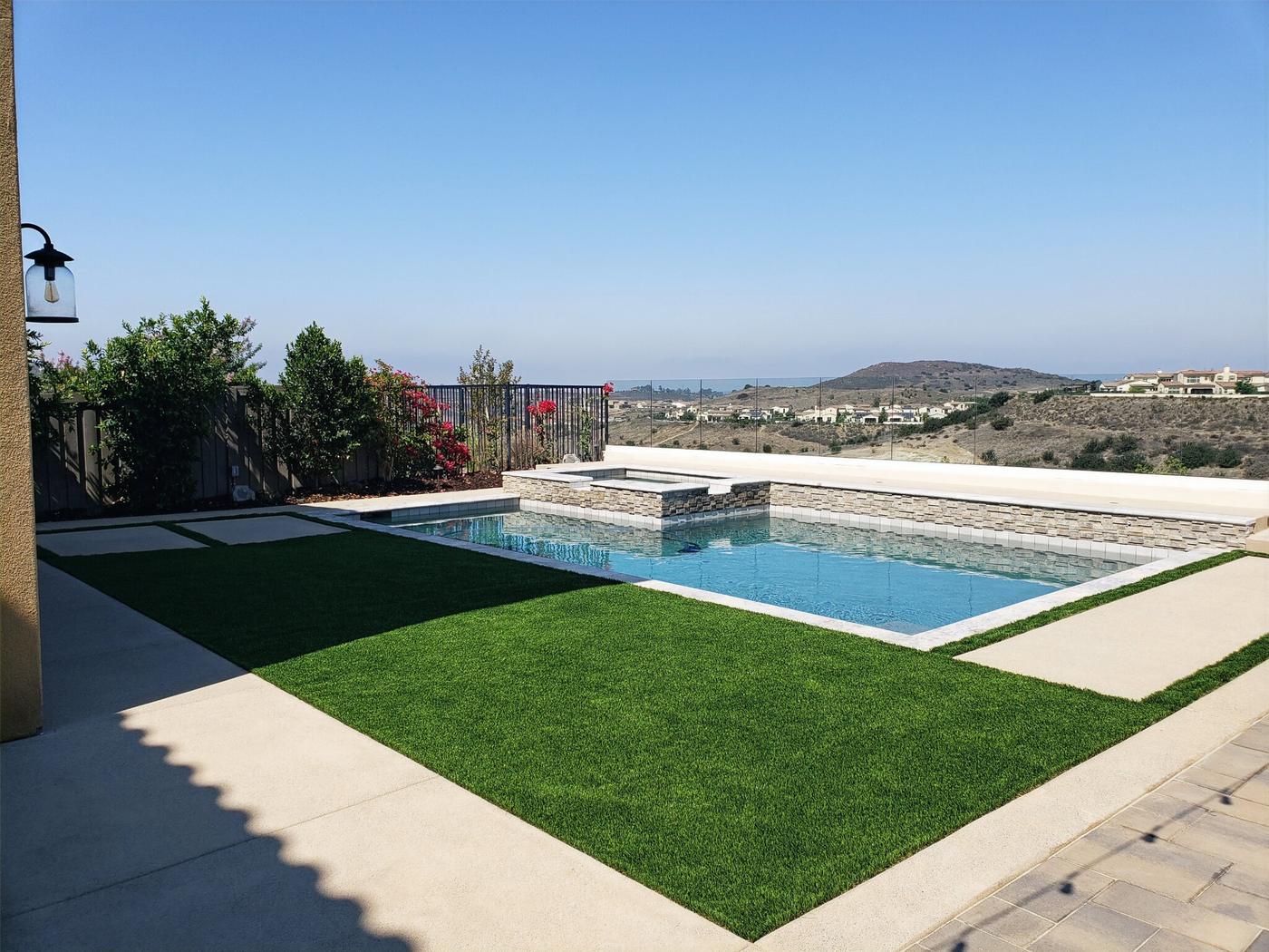 Pool and raised spa with synthetic lawn and a view