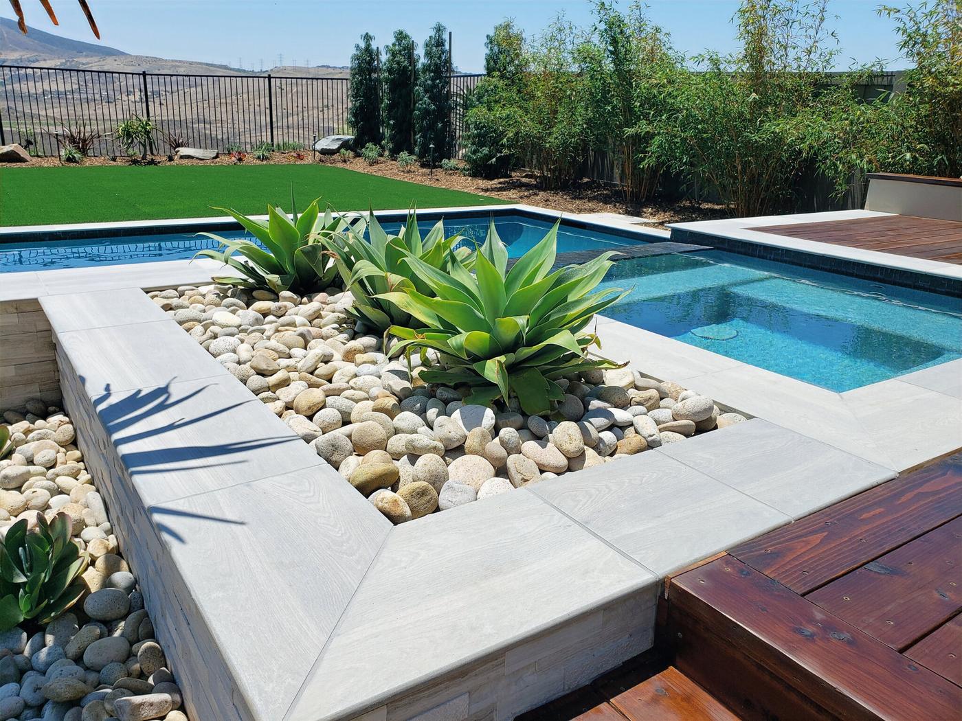 Pool and spa with an agave and river rock planter